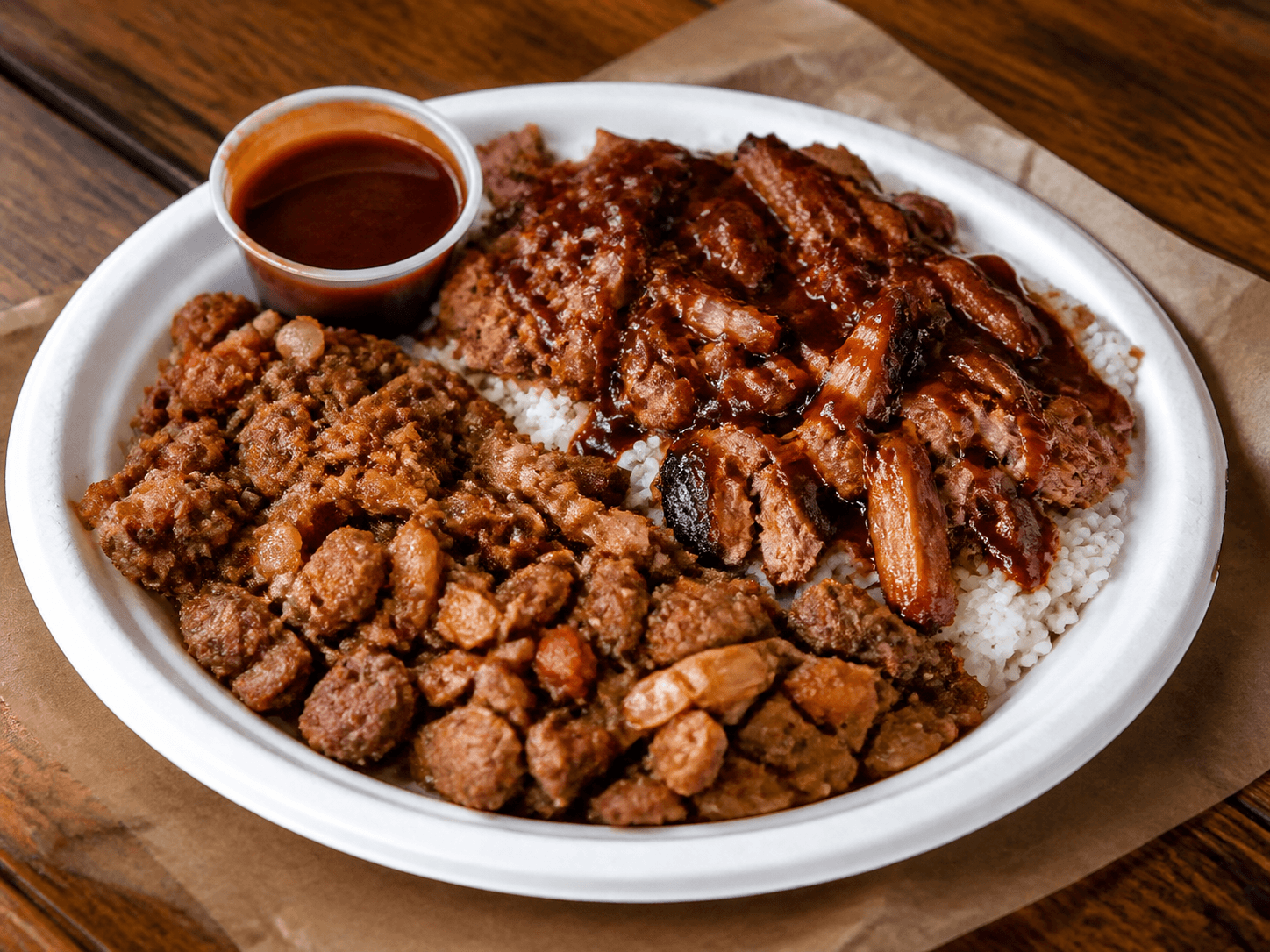 BBQ hash and rice plate with smoked meat and sauce in a takeout-style plate.