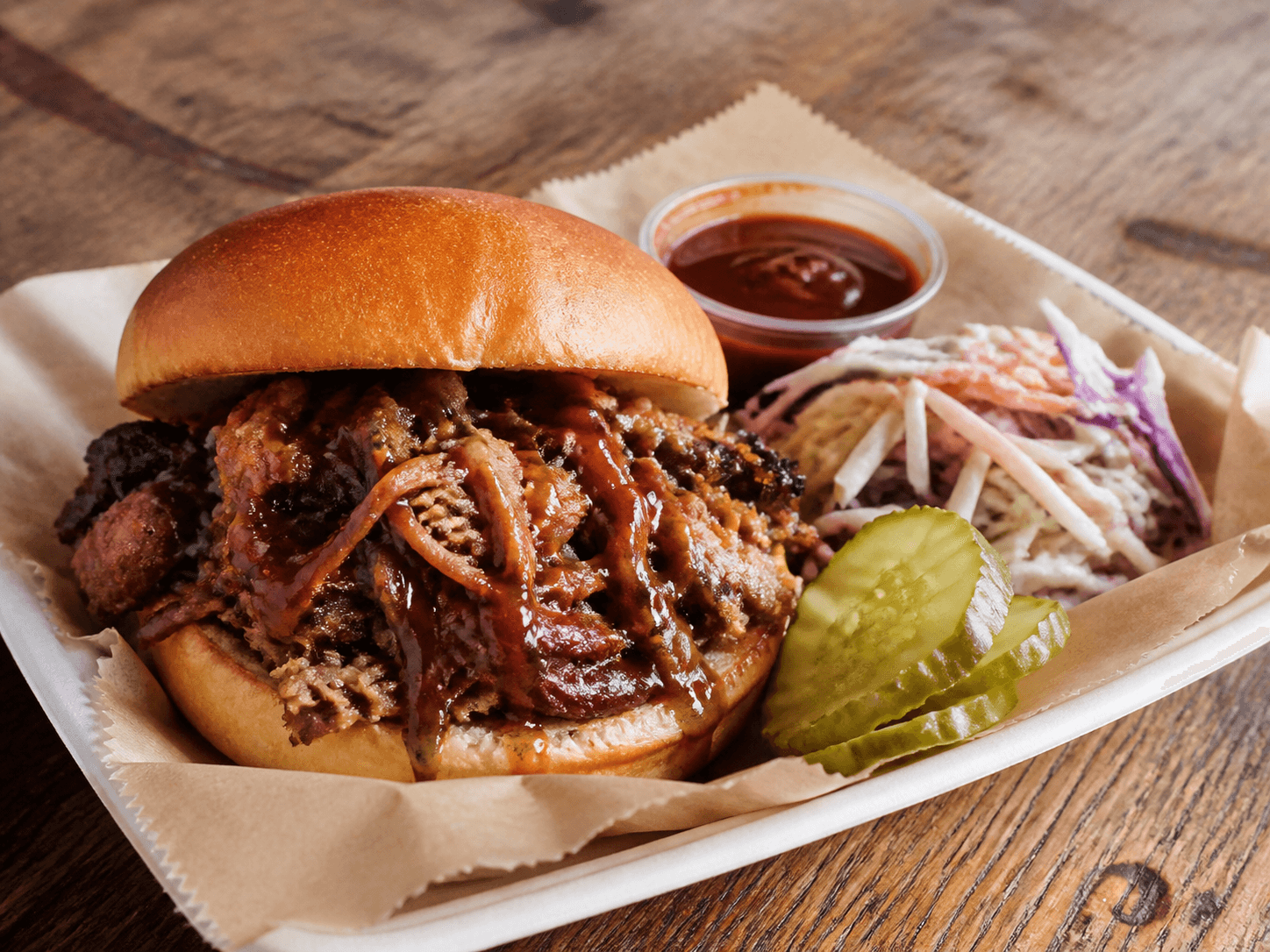 Pulled pork sandwich with slaw, pickles, and barbecue sauce.